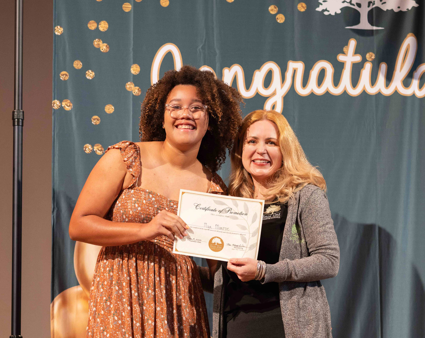 young woman posing w teacher receiving diploma from sage oak